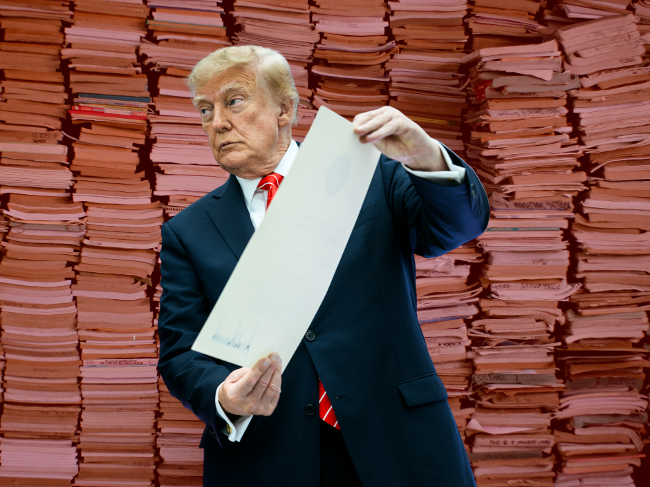 President Trump holding a document in front of stacks of books