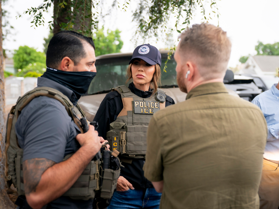 Image of Kristi Noem talking to masked agents.