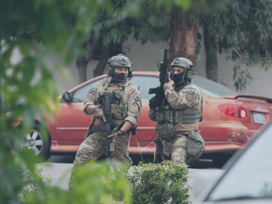 Image of masked immigration agents who are wearing masks and carrying guns.