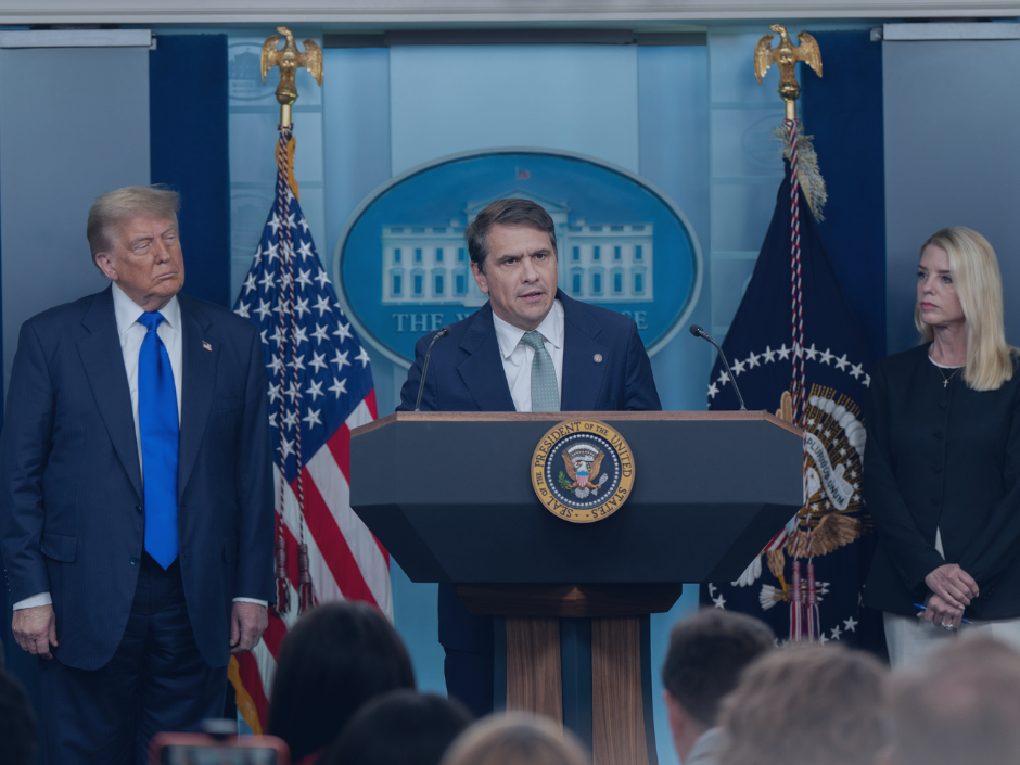 Todd Blanche at a podium next to Donald Trump and Pam Bondi.